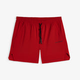 A front view of The Shorts in red, laid flat on a white background. The image highlights the elasticated waistband with a black drawstring, side pockets, notched hems, and the black c'est normal logo.
