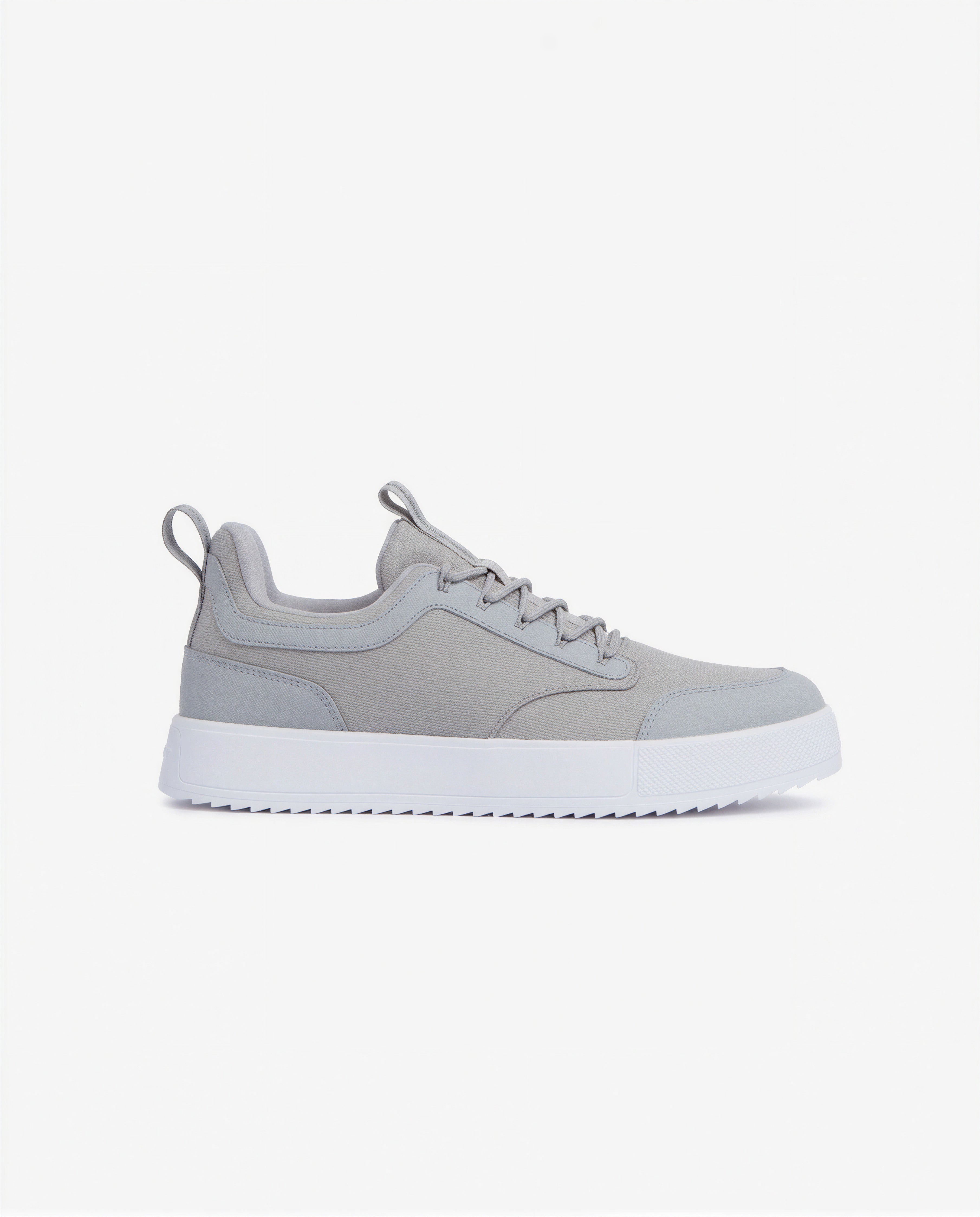 A side view of The Dynamic Waterproof Sneaker 2.0 Low in grey, placed on a white background. The image highlights the sleek waterproof upper, lace-up design, and the thick white EVA rubber grid sole.