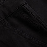 A detailed close-up of The Carpenter Pant in black, highlighting the woven fabric texture, reinforced stitching, and the subtle c'est normal logo.