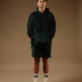 The Teddy Shorts in pine — worn with a matching hoodie and white sneakers