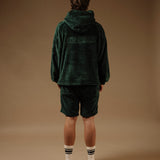 The Oversized Teddy Hoodie in pine — back view showing the embossed C'est normal logo