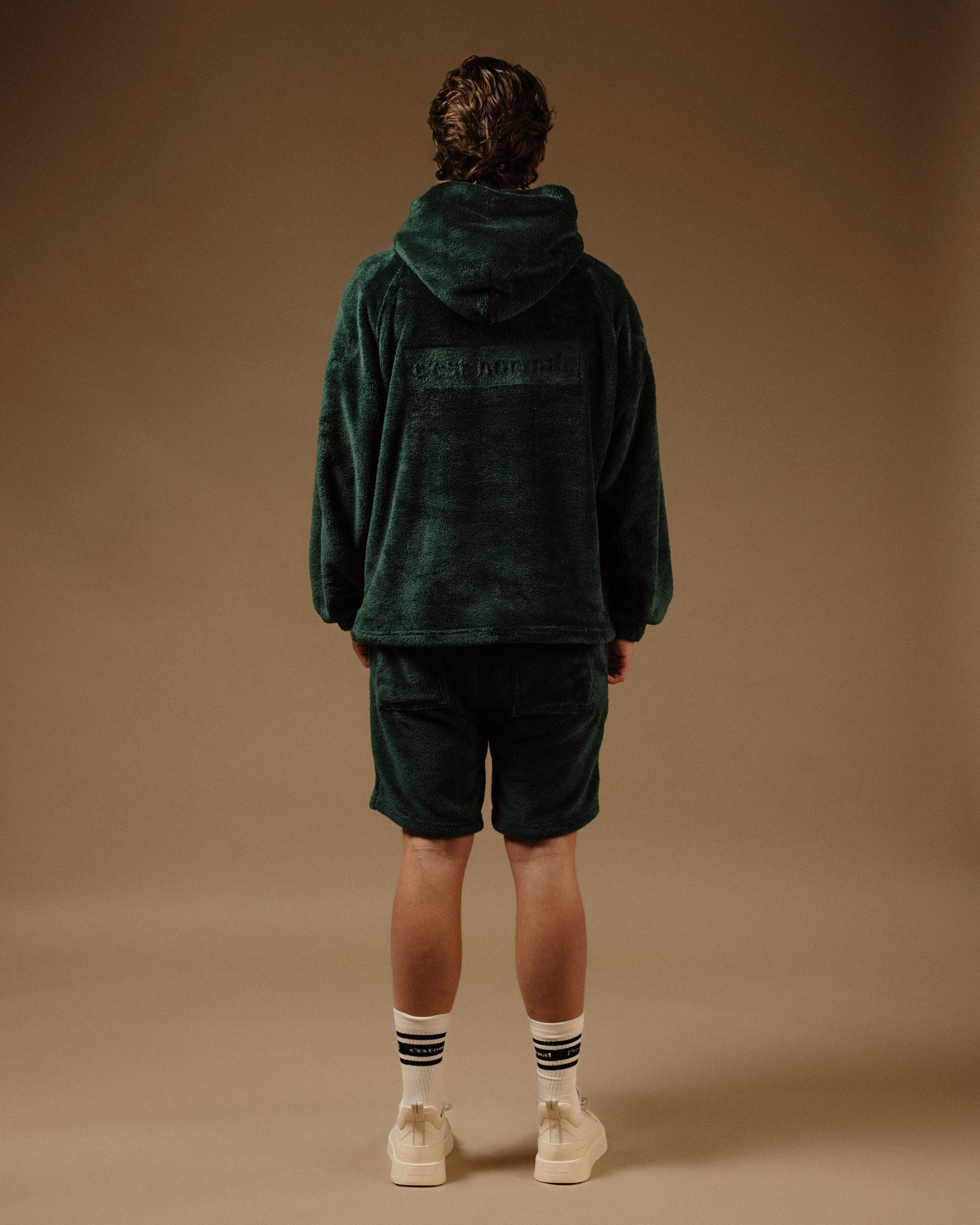 The Oversized Teddy Hoodie in pine — back view showing the embossed C'est normal logo