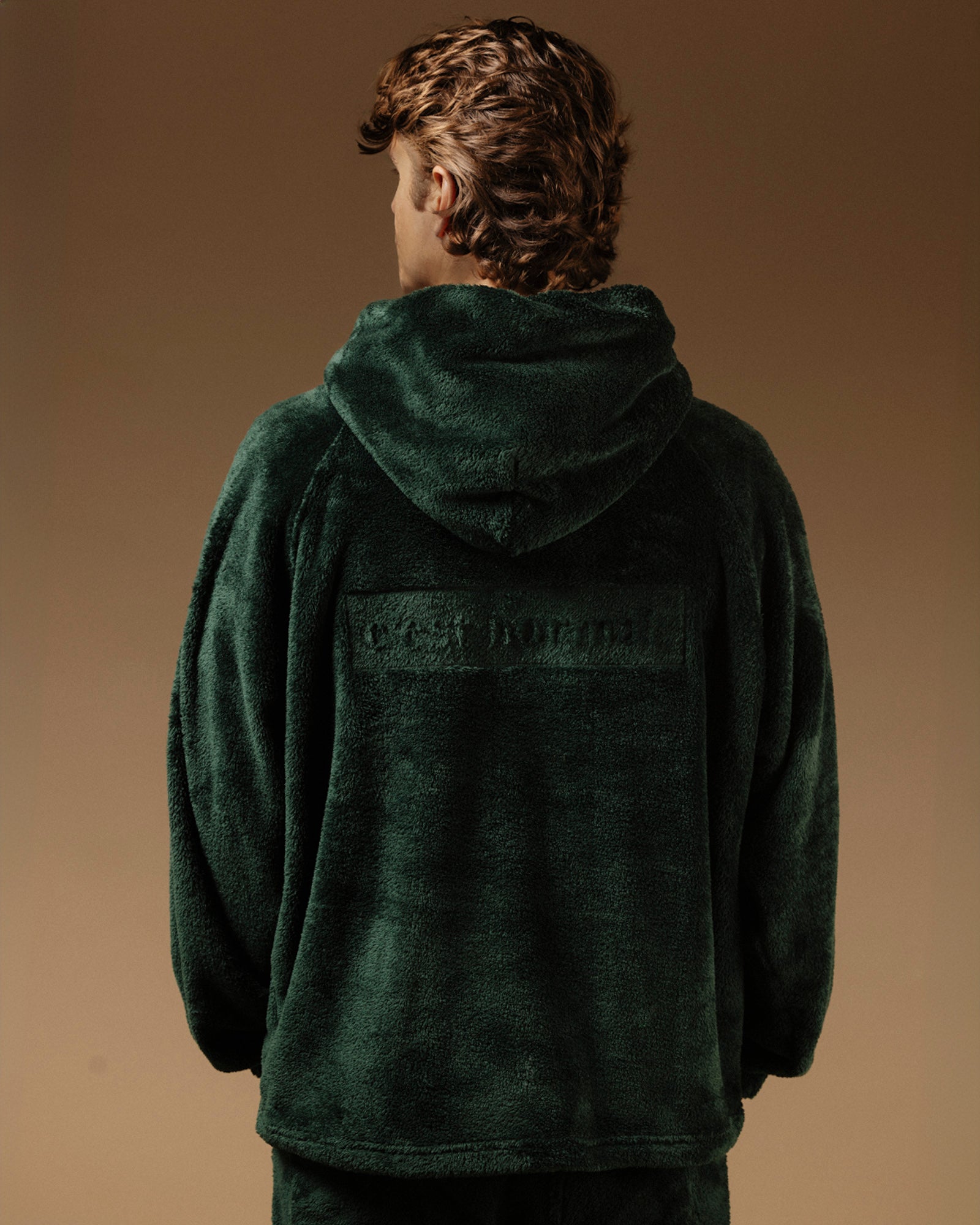 The Oversized Teddy Hoodie in pine — back view with the embossed C'est normal logo