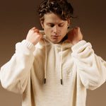 The Oversized Teddy Hoodie in cream — worn by a model adjusting the hood and drawstrings