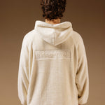 The Oversized Teddy Hoodie in cream — back view showing the embossed C'est normal logo