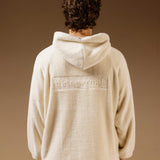 The Oversized Teddy Hoodie in cream — back view showing the embossed C'est normal logo