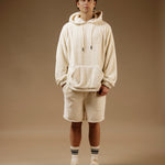 The Oversized Teddy Hoodie in cream — worn with matching shorts and white sneakers