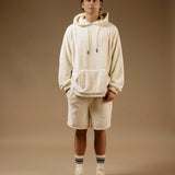 The Oversized Teddy Hoodie in cream — worn with matching shorts and white sneakers