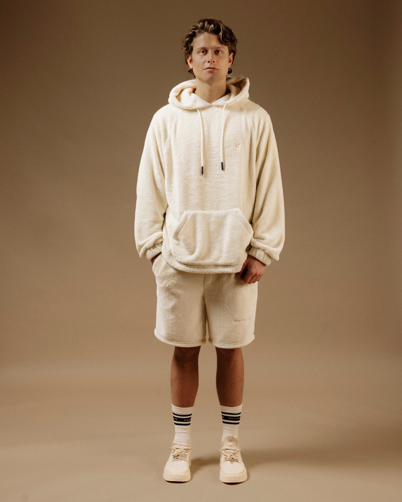 The Oversized Teddy Hoodie in cream — worn with matching shorts and white sneakers