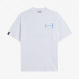 Le Linen T-Shirt in white — oversized fit with a blue chest logo and black cuff tag