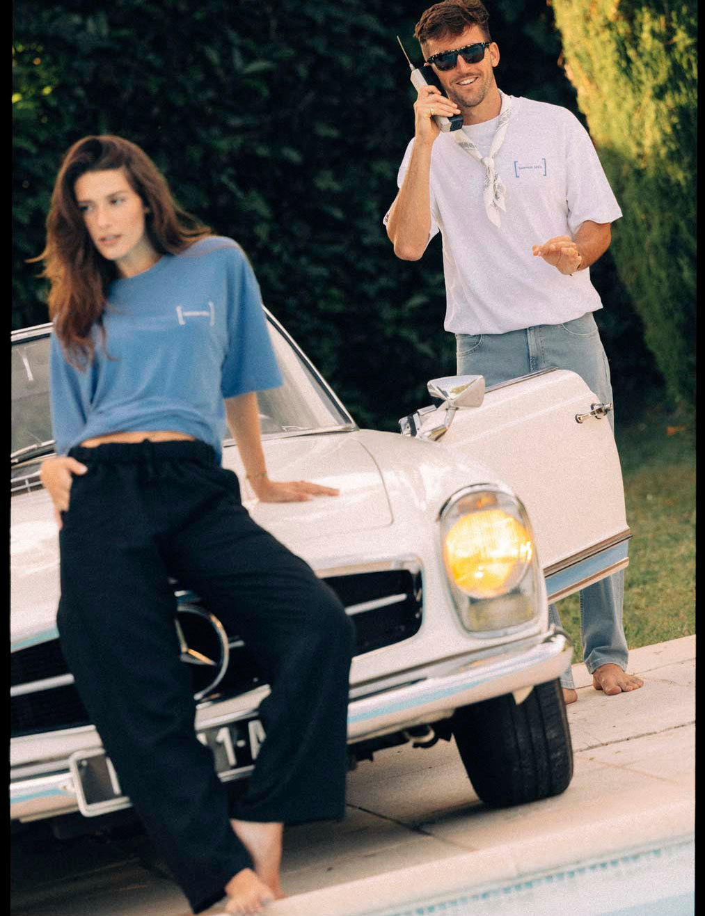 Le Linen T-Shirt in white — worn by a man holding a vintage phone near a classic car
