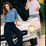 Le Linen T-Shirt in white — worn by a man holding a vintage phone near a classic car