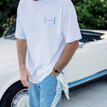 Le Linen T-Shirt in white — worn with blue jeans next to a white vintage car