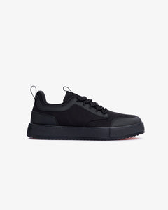 A side profile view of The Dynamic Waterproof Sneaker 2.0 Low in black, placed on a white background. The image showcases the shoe's sleek waterproof upper, padded collar, and thick black midsole.