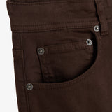 A close-up shot of the front and coin pockets on The 5 Pocket Pants in brown. The image highlights the branded rivets featuring the c'est normal logo and a touch of orange accent stitching.