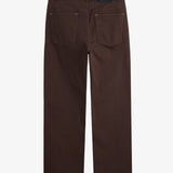 A back view of The 5 Pocket Pants in brown, laid flat on a white background. The image highlights the two back pockets, belt loops, orange accent stitching, and the black rubber patch with the white c'est normal logo.