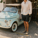 The Board Shorts in khaki — worn with a white linen shirt next to a vintage light blue car