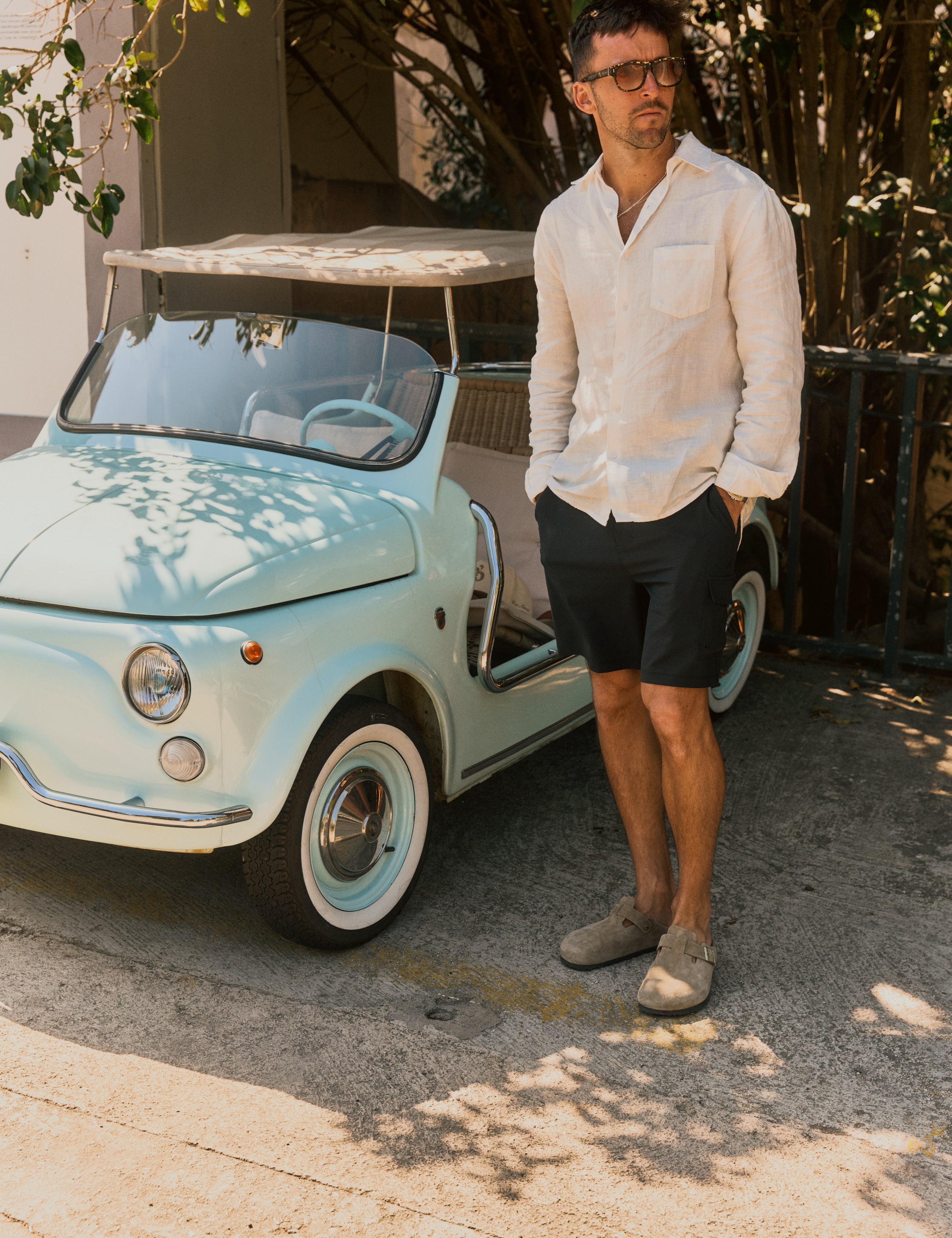 The Board Shorts in khaki — worn with a white linen shirt next to a vintage light blue car