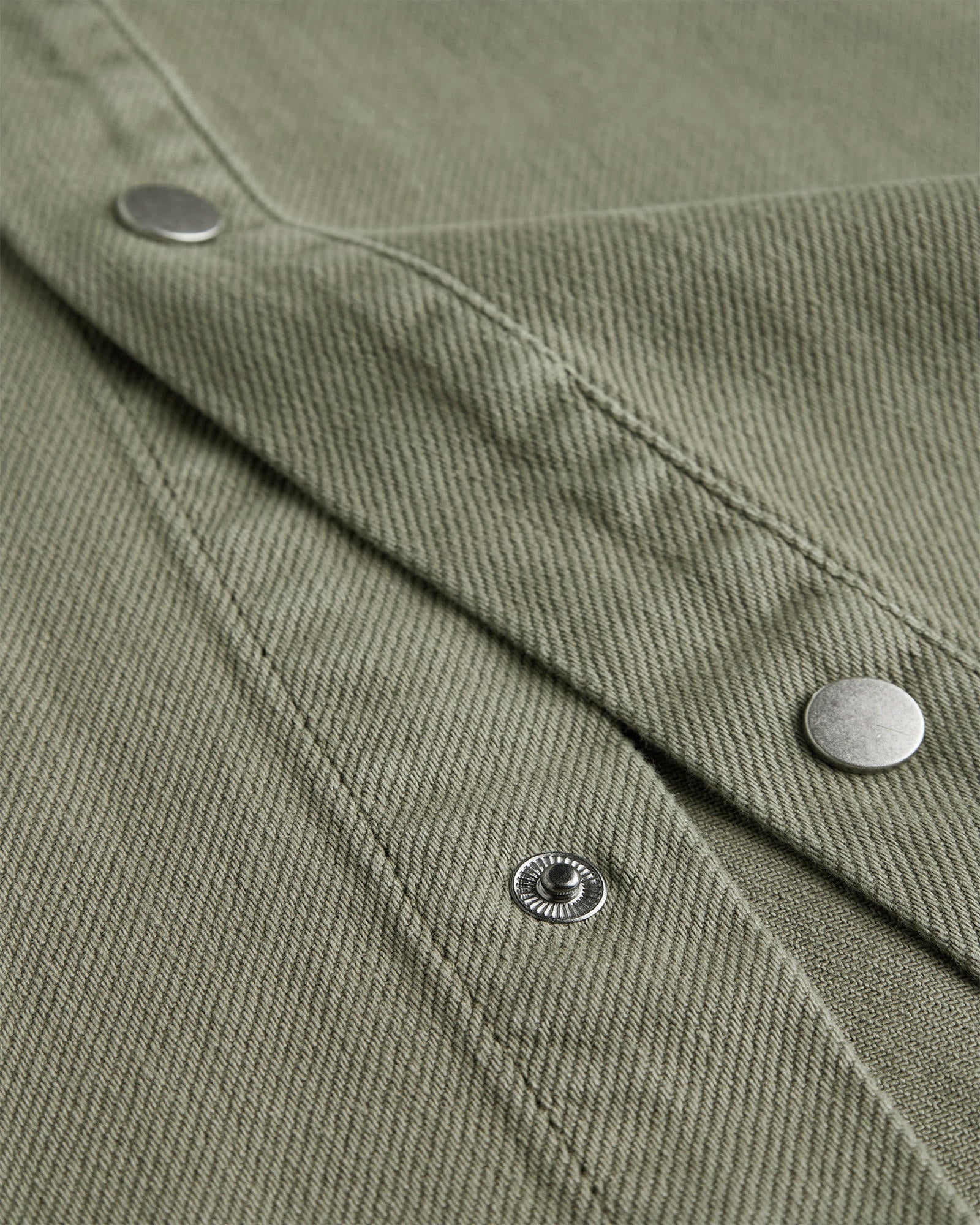 The Bilbao Overshirt in olive — close-up of the textured fabric and snap buttons