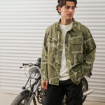 The Bilbao Overshirt in camo — worn while standing next to a vintage motorcycle