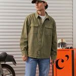 The Bilbao Overshirt in olive — styled with blue jeans and a cap next to a motorcycle