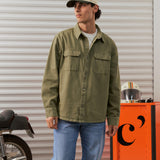 The Bilbao Overshirt in olive — styled with blue jeans and a cap next to a motorcycle