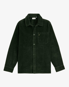 A front view of The CÔTELÉ Corduroy Overshirt in forest green, laid flat on a white background. The image highlights the corduroy texture, button front, and single chest pocket with the c'est normal logo.