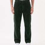 The Daily Cord Chino in forest green — front model view wearing white sneakers