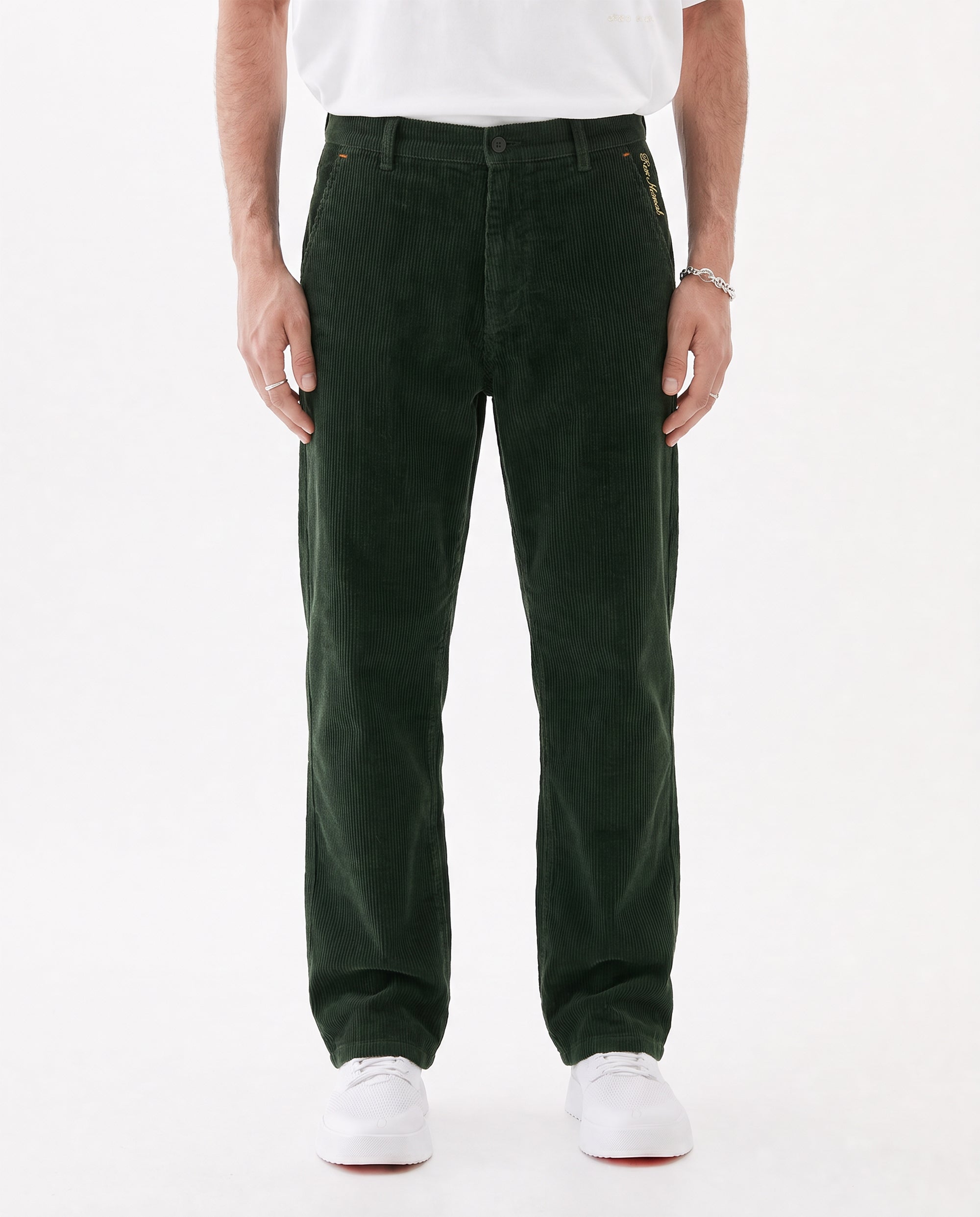 The Daily Cord Chino in forest green — front model view wearing white sneakers
