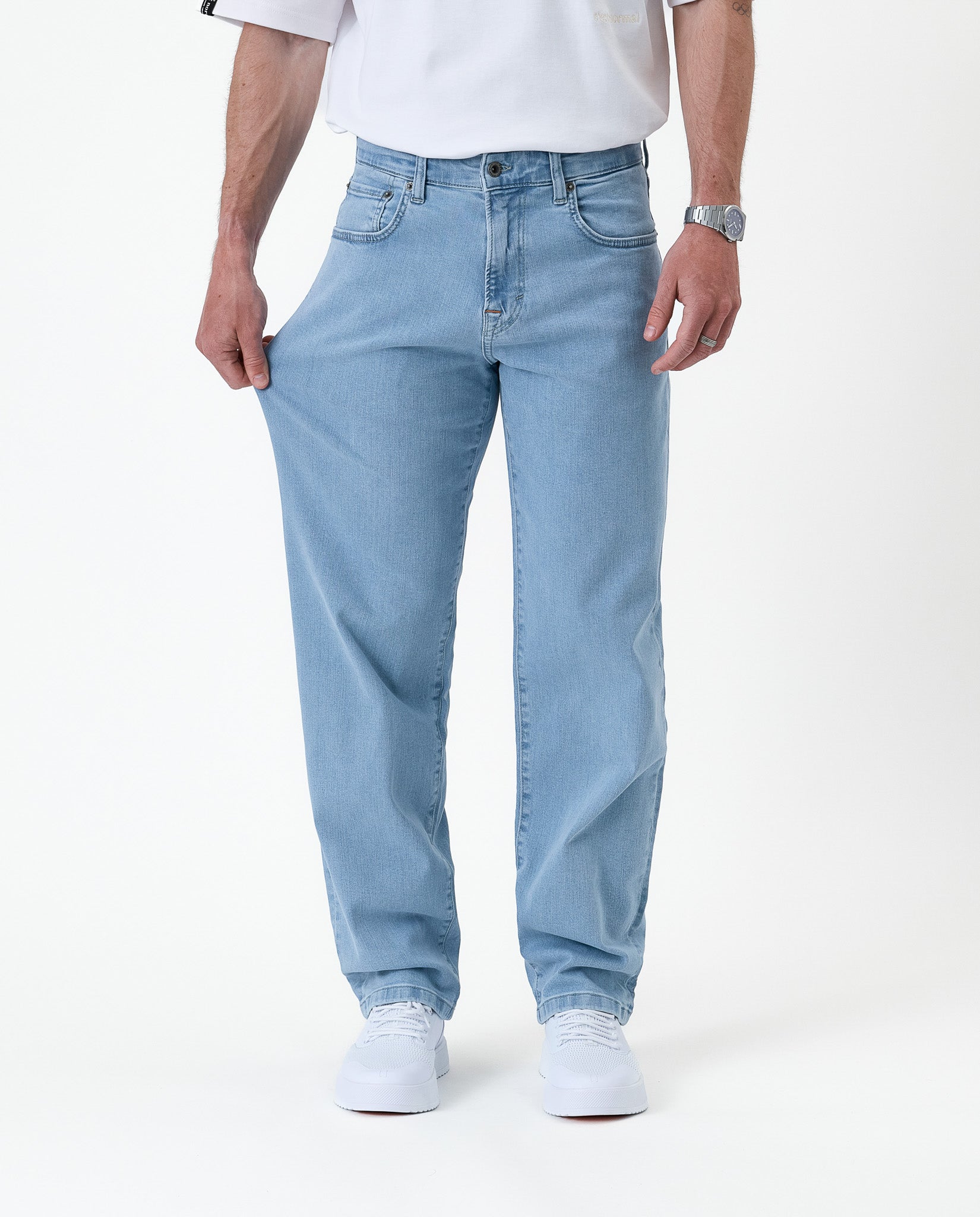 The Jeans Relaxed Straight Fit in light blue — stretching the denim fabric to show flexibility