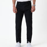 The Jeans Slim Fit in jet black — front view worn with white sneakers