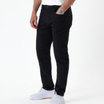 The Jeans Slim Fit in Jet Black — front view worn with white sneakers