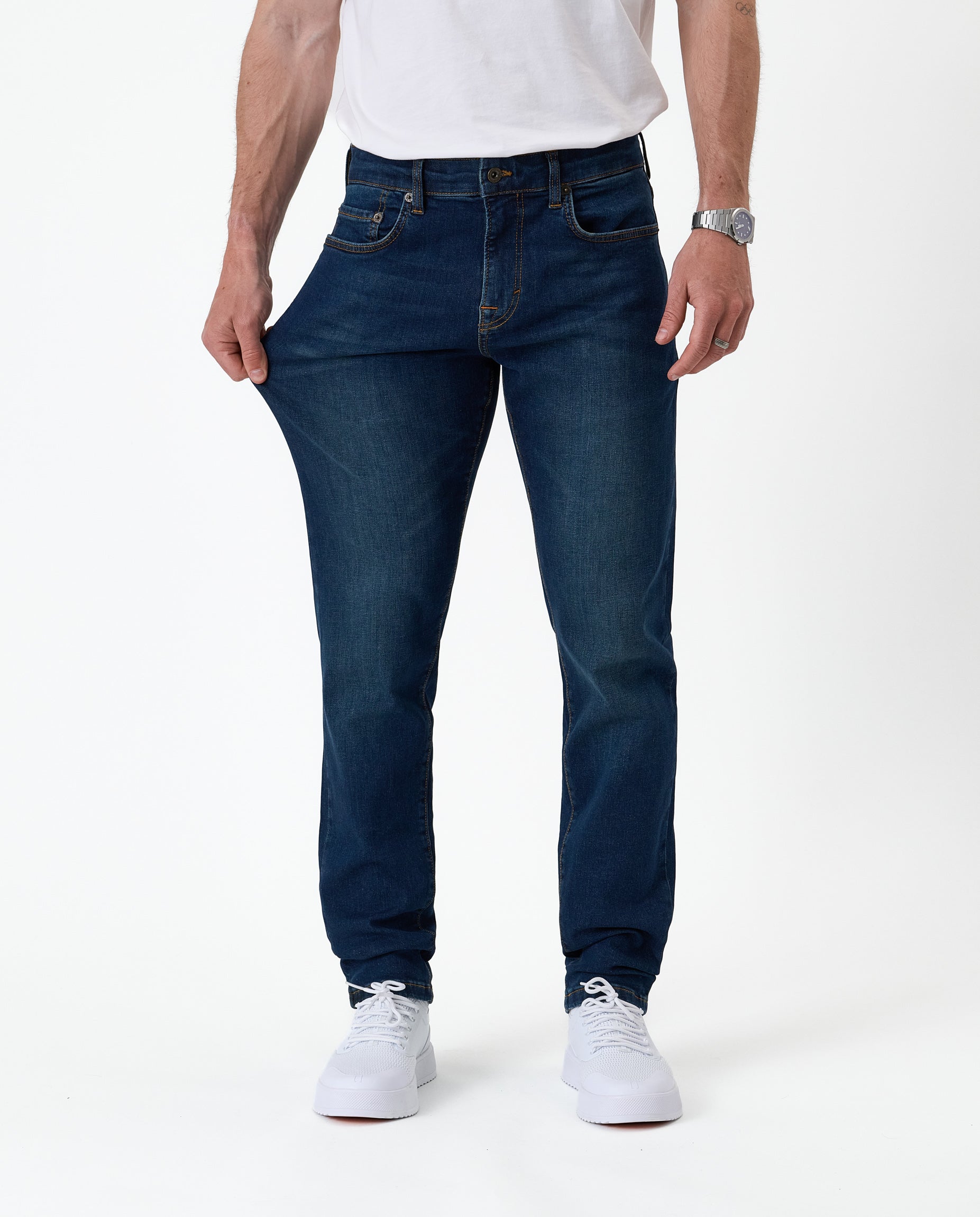 The Jeans Slim Fit in Midwash — model pulling the fabric to demonstrate stretch