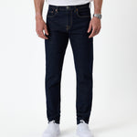 The Jeans Slim Fit in rinse wash — front view with white sneakers