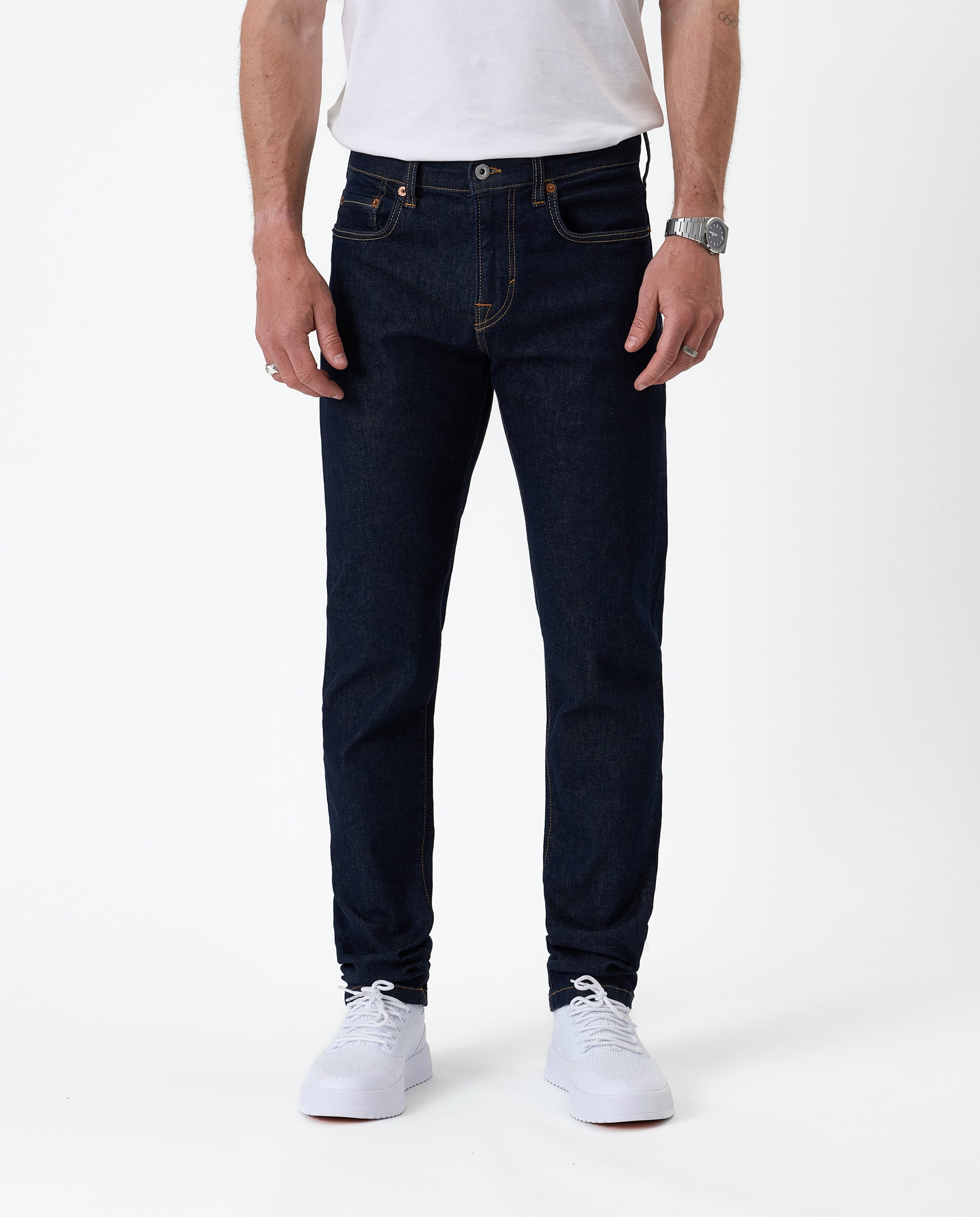 The Jeans Slim Fit in rinse wash — front view with white sneakers