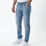The Jeans Slim Fit in light midwash — worn with white sneakers
