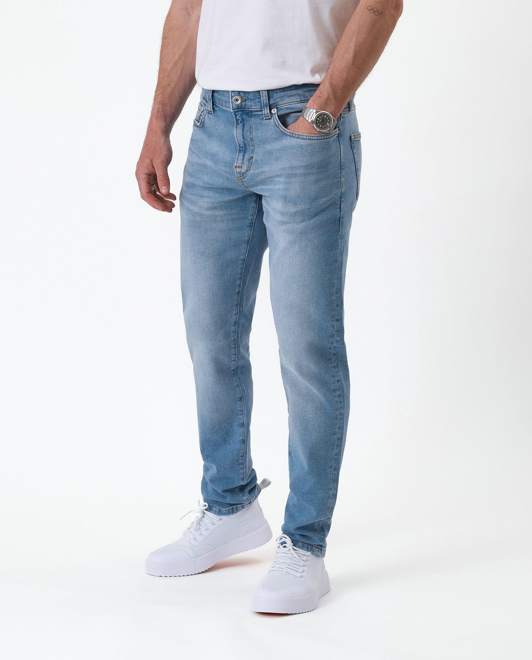 The Jeans Slim Fit in light midwash — worn with white sneakers