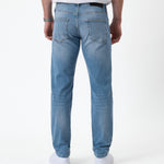 The Jeans Slim Fit in light midwash — back view with the black C'est normal rubber patch