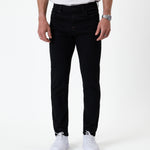 The Jeans Skinny Fit in jet black — front view worn with white sneakers