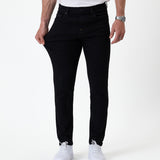 The Jeans Skinny Fit in jet black — pulling at the thigh to show the fabric's stretch