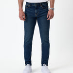 The Jeans Skinny Fit in Midwash — front view worn with white sneakers