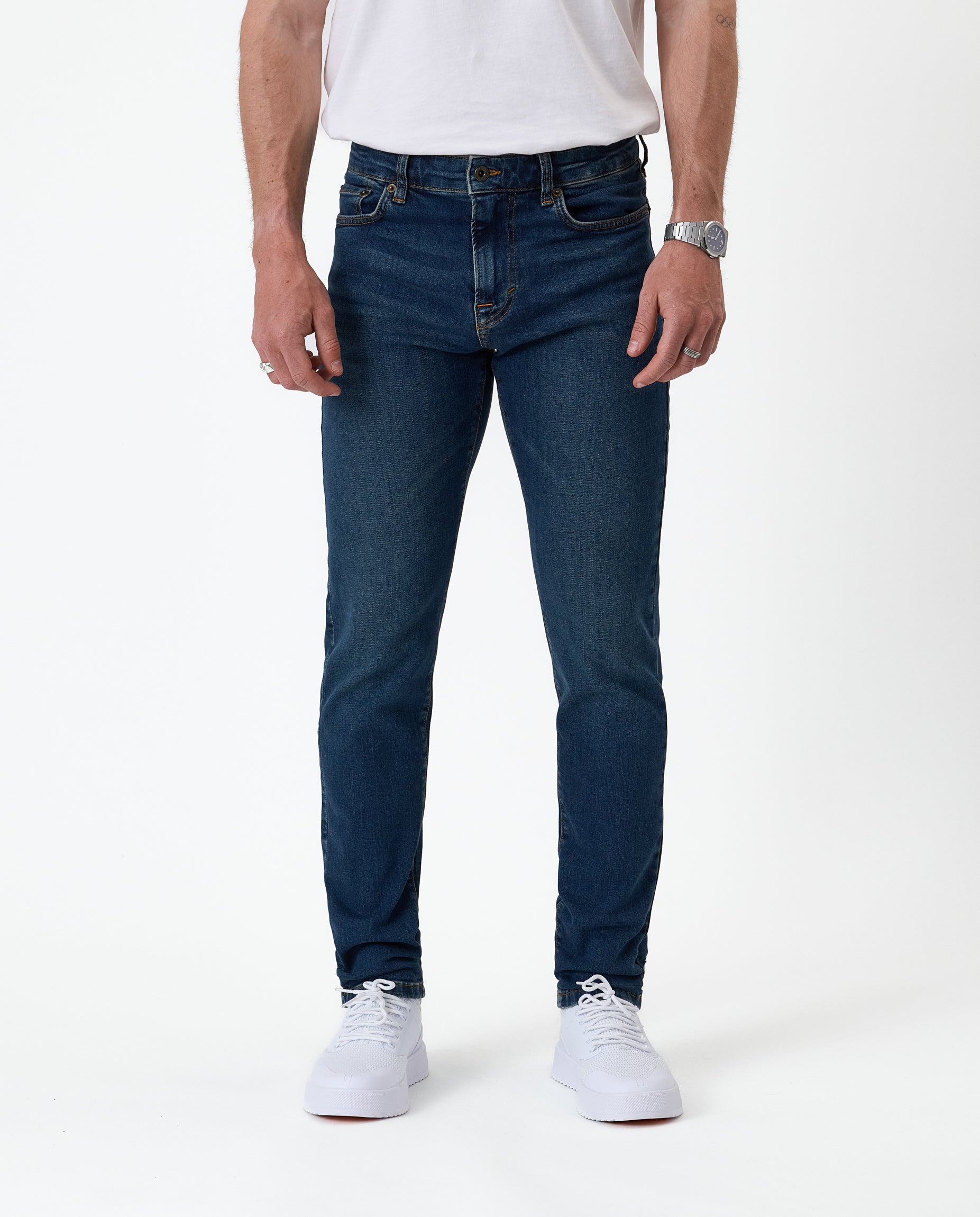 The Jeans Skinny Fit in Midwash — front view worn with white sneakers