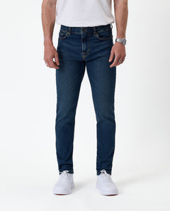 The Jeans Skinny Fit in Midwash — front view worn with white sneakers