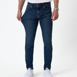The Jeans Skinny Fit in midwash — fabric being pulled to demonstrate stretch