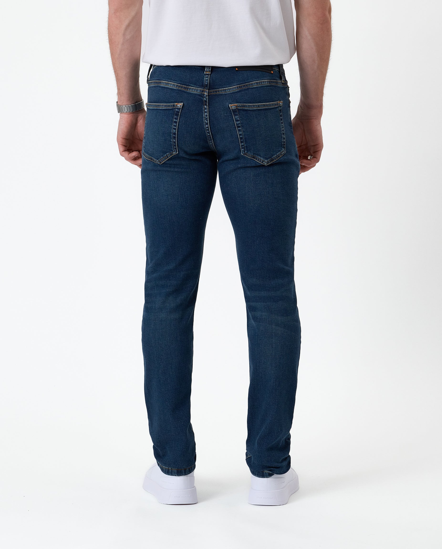 The Jeans Skinny Fit in midwash — back view worn with white sneakers