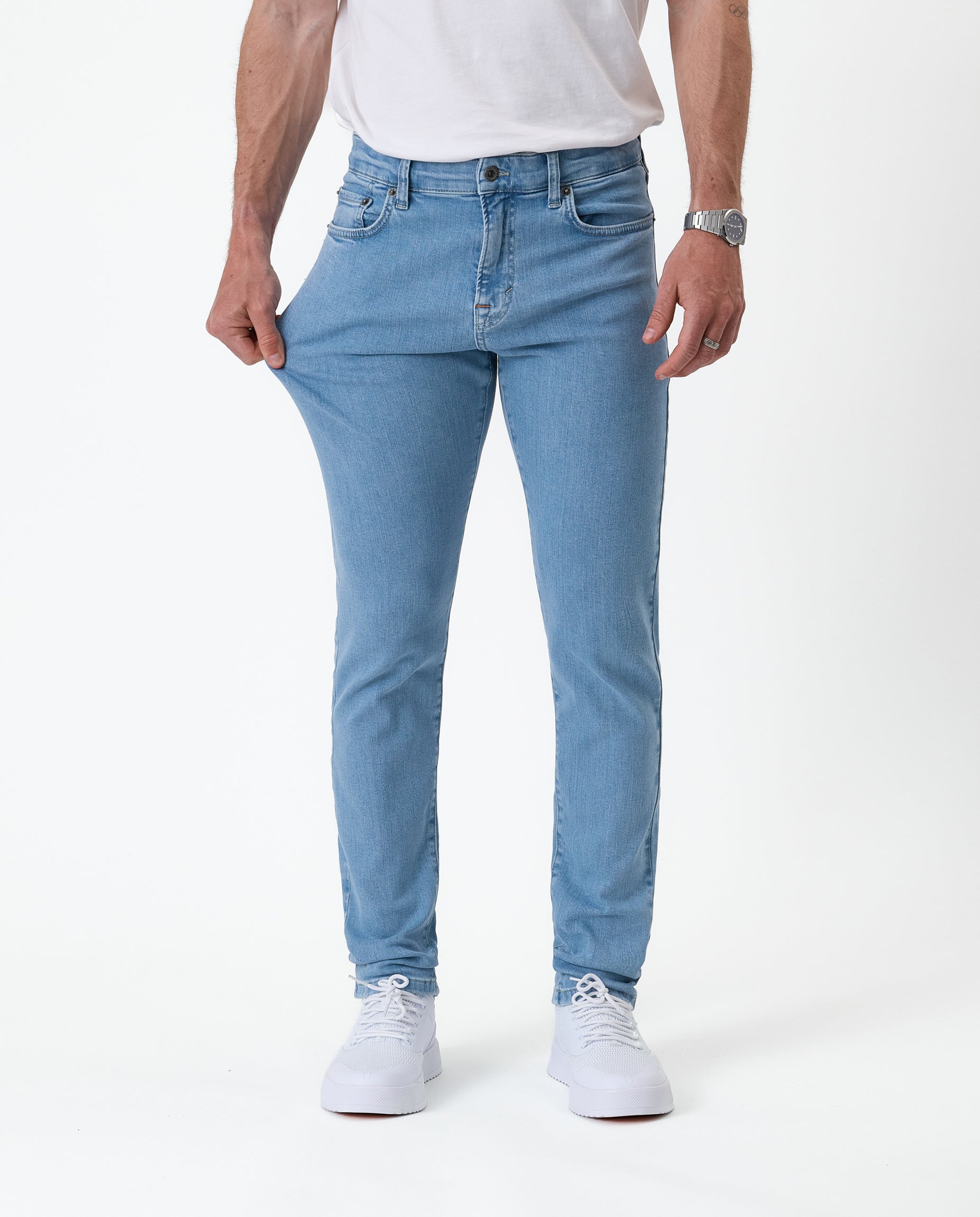 The Jeans Skinny Fit in light blue — stretching the fabric to show the flexible Motion Fabric