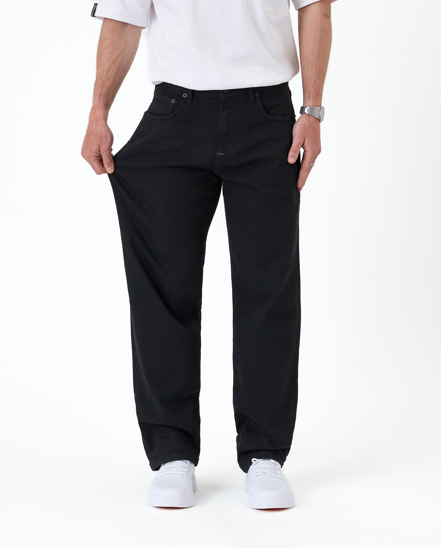 The Jeans Relaxed Straight Fit in jet black — demonstrating the stretch fabric at the thigh