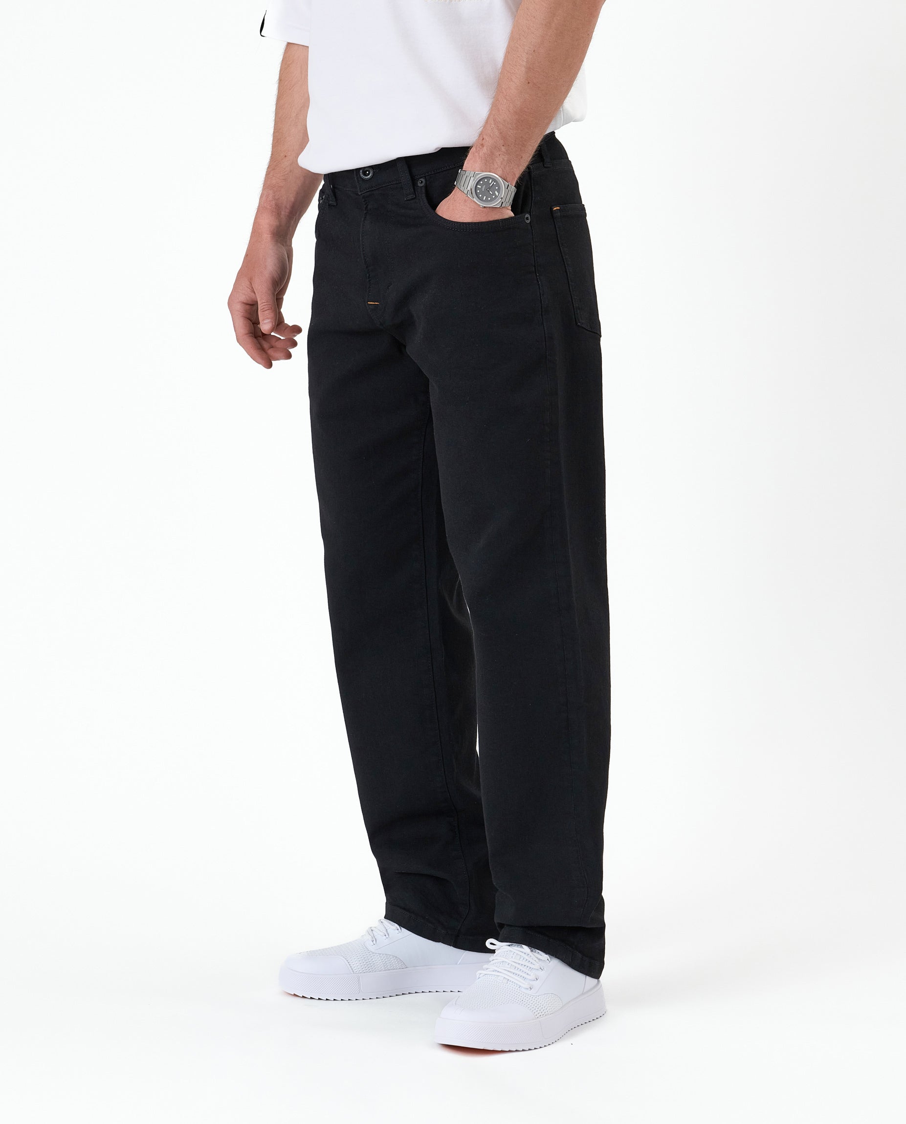 The Jeans Relaxed Straight Fit in jet black — side view worn with white sneakers