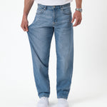The Jeans Relaxed Straight Fit in Light Midwash — pulling the leg to show the stretch fabric