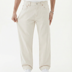 The Jeans Relaxed Straight Fit in ecru — model pulling at the leg to show fabric stretch